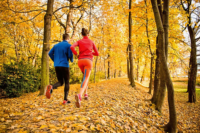 Paar joggt durch einen Wald im Herbst